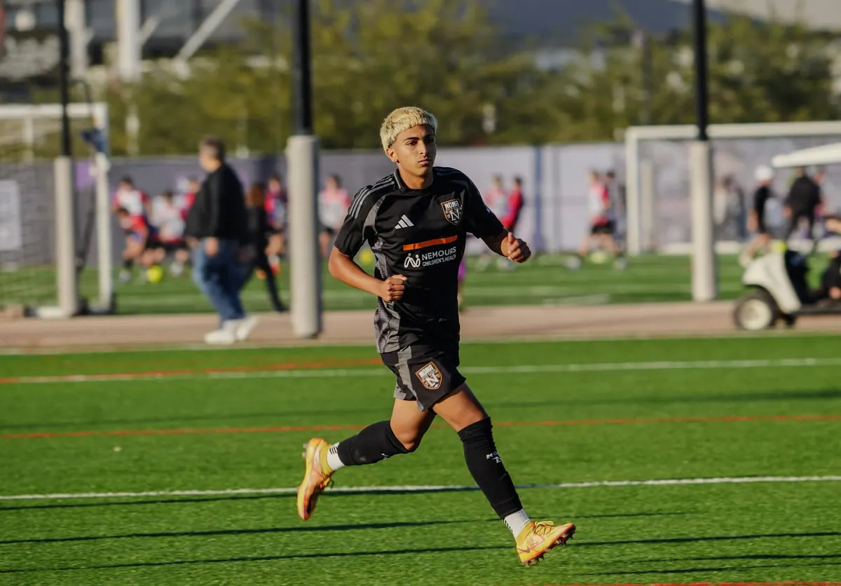 Atleta de uniforme preto correndo em campo de grama sintética