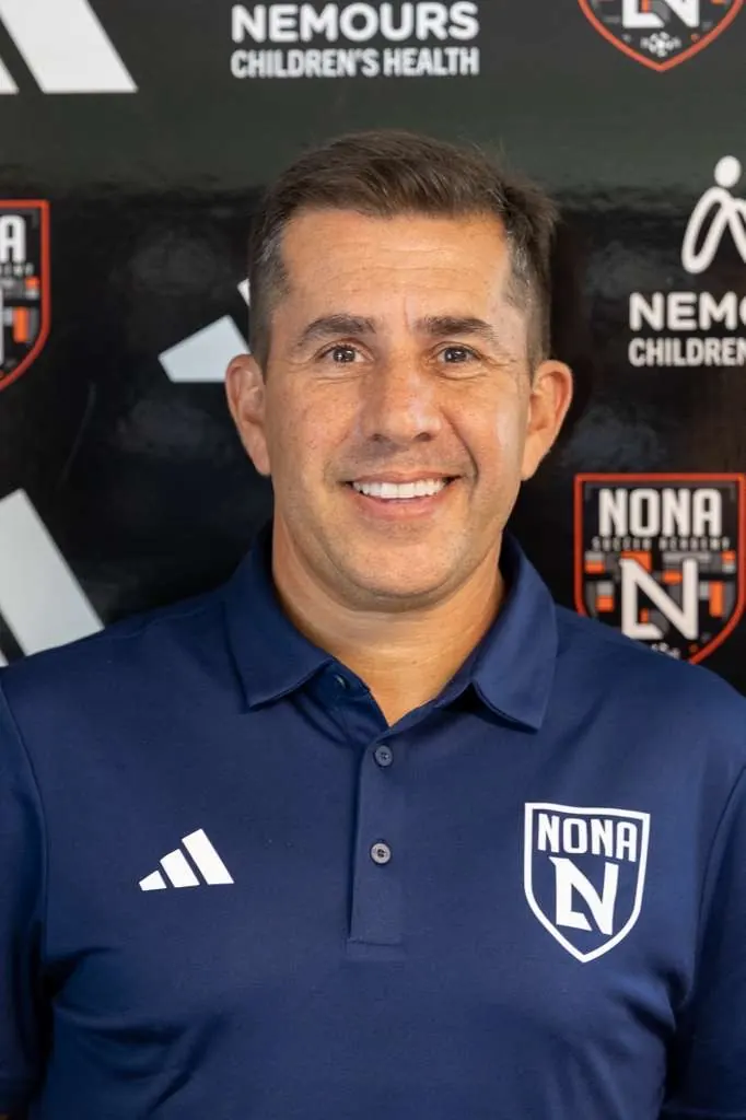 Edson Sesma, o Edinho, diretor executivo da Nona Soccer Academy, sorrindo, com camisa polo azul-marinho do clube